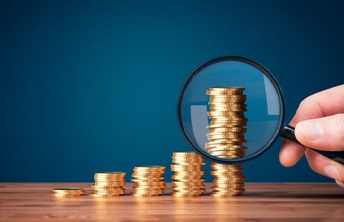 Magnifying glass inspecting increasingly taller stacks of coins