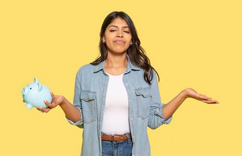 Woman holding a piggy bank and shrugging
