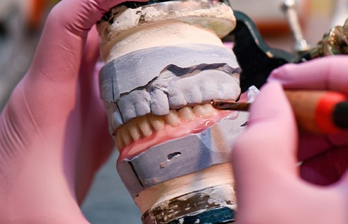 A dental lab technician carving wax dentures
