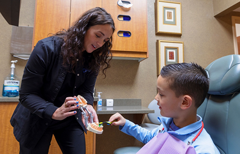 Young boy shaking hands with his dentist while sitting in his mothers lap