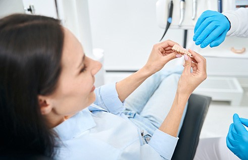 Dentist showing model teeth to patient