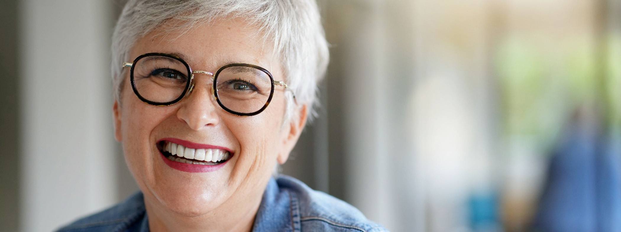 Woman with short gray hair in black-framed glasses smiling