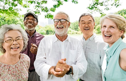 Group of adults together outside smiling under a tree