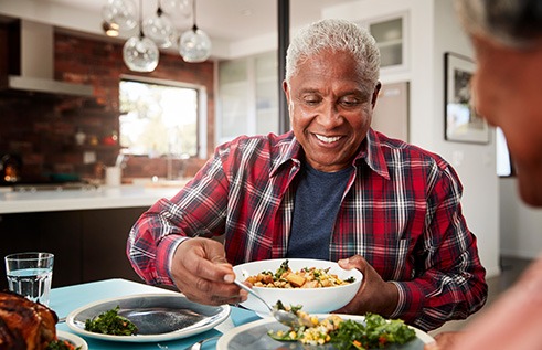Senior man filling plate at table
