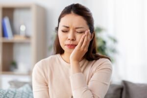 Woman holding jaw in pain.